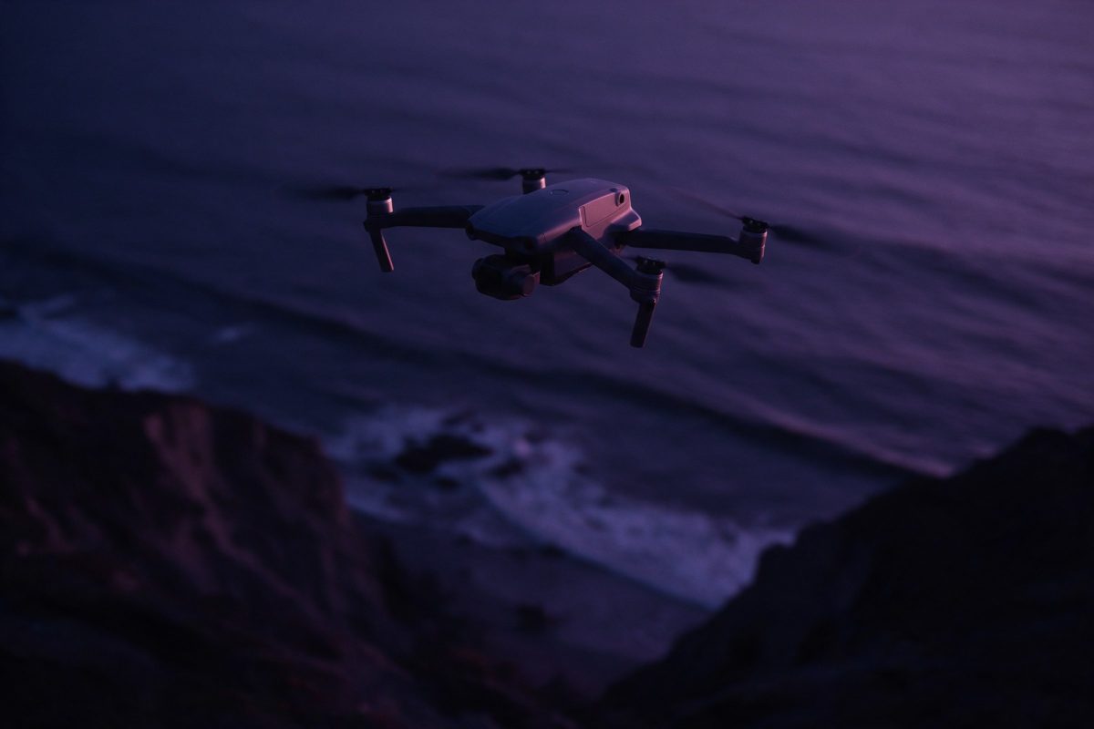 Alacakaranlıkta deniz ve kayalıklar üzerinde havada duran drone